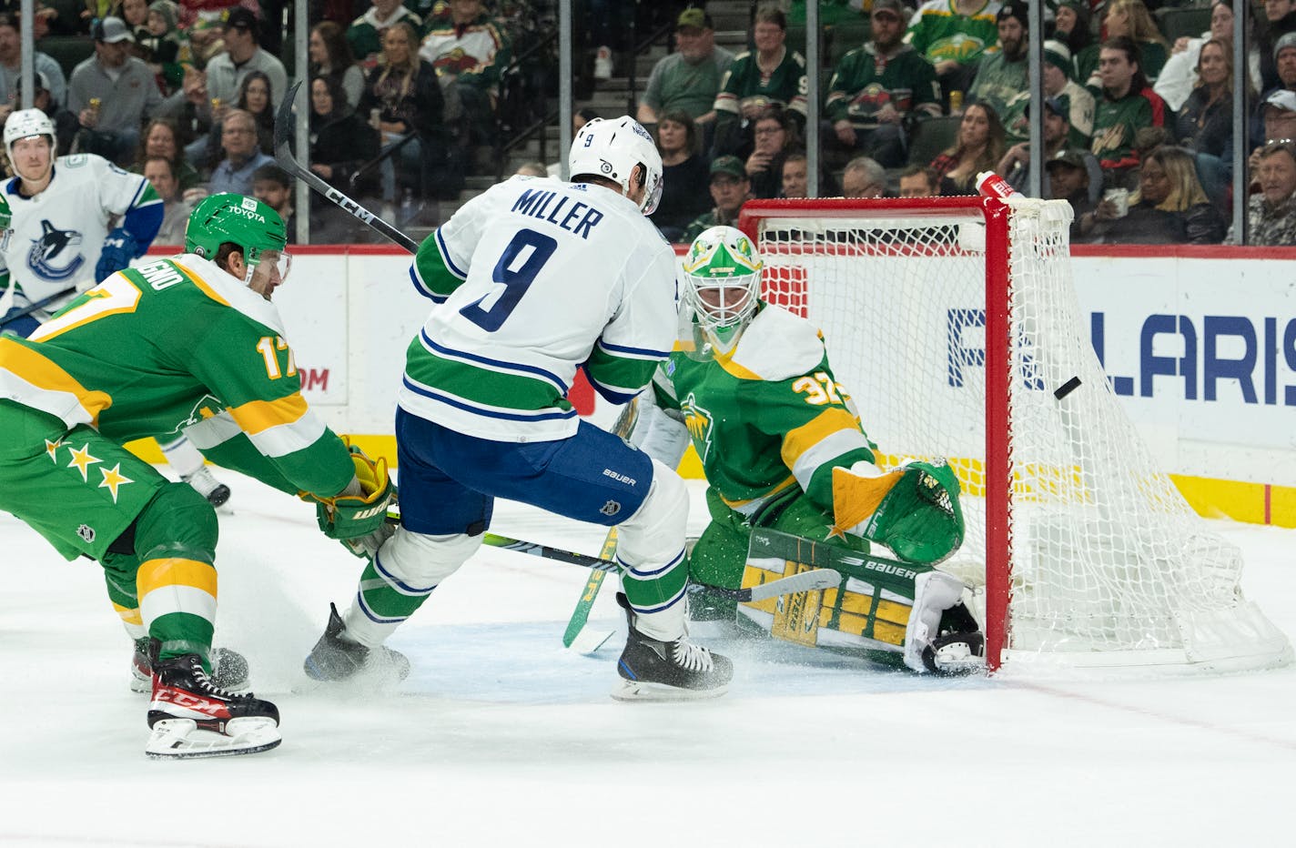 Wild goaltender Filip Gustavsson watched the puck go wide of the net while Vancouver center J.T. Miller waited for a rebound in the first period.