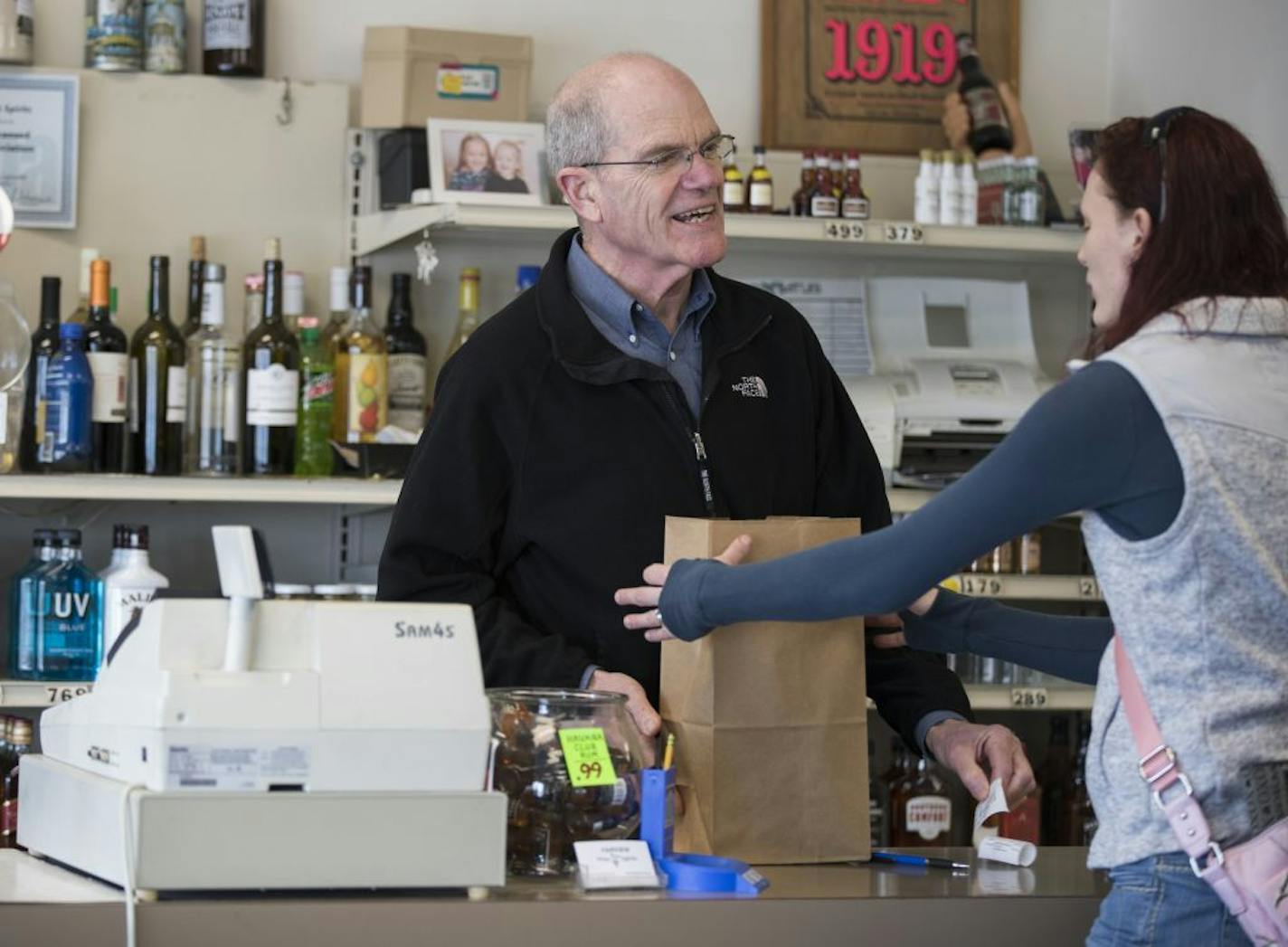 Steve Burwell, the owner of Fairview Wine and Spirits in Roseville, helps a customer.