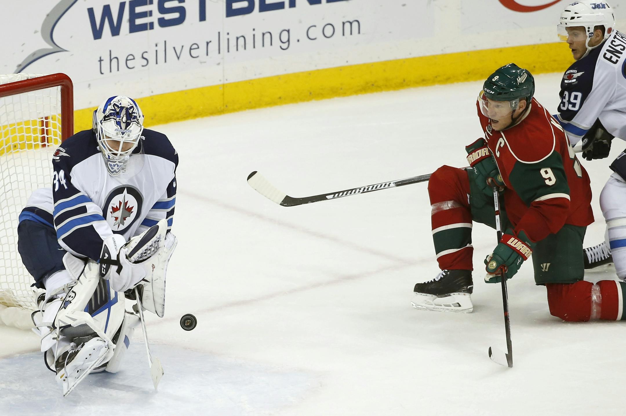 Winnipeg Jets goalie Michael Hutchinson (34) deflects a shot by Minnesota Wild center Mikko Koivu (9), of Finland, as Jets defenseman Tobias Enstrom (39), of Sweden, watches during the third period of an NHL hockey game in St. Paul, Minn., Tuesday, Nov. 10, 2015. The Wild won 5-3. (AP Photo/Ann Heisenfelt)