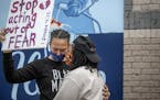 Asha Knight, left, is comforted by Dilonna Johnson, Tuesday, May 26, 2020, in Minneapolis, near the site where a black man, who was taken into police 
