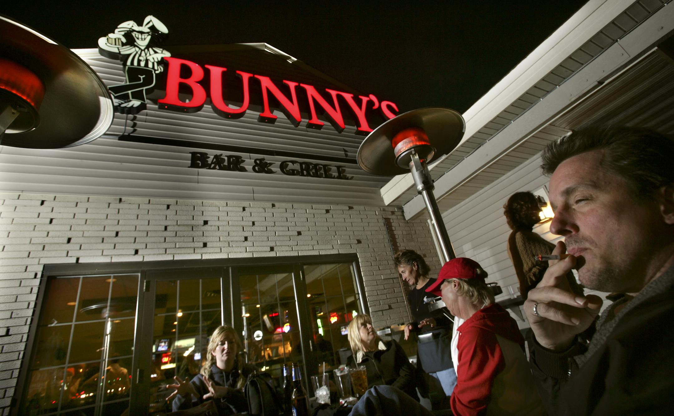 Joel koyama&#xd4;jkoyama@startribune.com Metro bars and clubs are bracing for their first winter with the smoking ban. Some are adding patios and heat lamps to accomodate smokers, while others don't what they'll do. Mark Delambo of Hopkins, sits on the patio under a heat lamp while he takes a drag off his cigarette at Bunny's bar and grill in St. Louis Park. From Right to Left, Mark Delambo (Hopkins), Cheri Schieck (St. Louis Park) in red, Jennie Schwochert (minneapolis) and Kasi Joyce (St. Loui