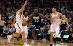 Minnesota Timberwolves forward Andrew Wiggins (22) drives between Phoenix Suns guard Mike James and Devin Booker (1) in the first half during an NBA b