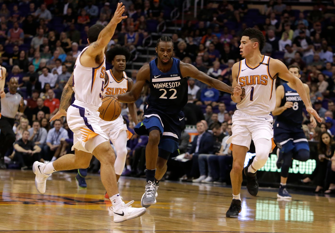 Minnesota Timberwolves forward Andrew Wiggins (22) drives between Phoenix Suns guard Mike James and Devin Booker (1) in the first half during an NBA basketball game, Saturday, Nov 11, 2017, in Phoenix. (AP Photo/Rick Scuteri)