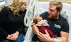 Andrew Goette, flanked by his wife Ashley. cradles his four-day-old son Lennon Andrew in his hospital bed. Andrew expects to be discharged as soon as 