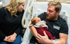 Andrew Goette, flanked by his wife Ashley. cradles his four-day-old son Lennon Andrew in his hospital bed. Andrew expects to be discharged as soon as 