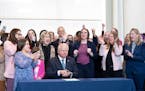 Surrounded by DFL legislators, Minnesota Gov. Tim Walz, center, signs a bill to add a “fundamental right” to abortion access into state law on Tue