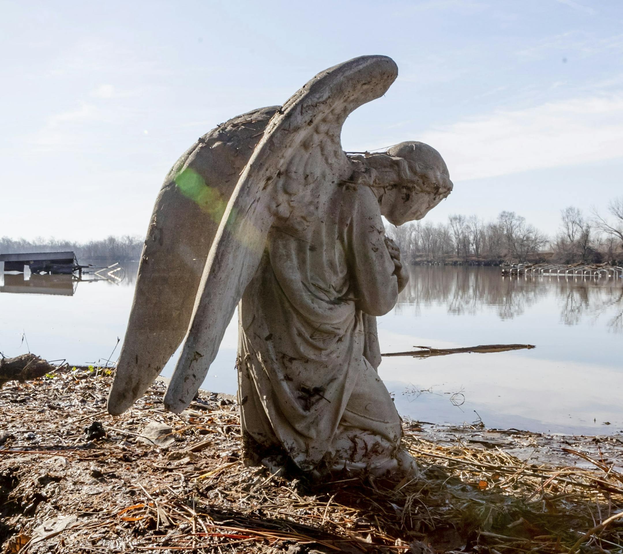 An angel statuary graces a yard near Hansen Lake Friday, March 22, 2019, in Bellevue, Neb. Residents were allowed into the area for the first time since floodwaters overtook several homes. Flooding in Nebraska has caused an estimated $1.4 billion in damage. The state received Trump's federal disaster assistance approval on Thursday. (Kent Sievers/Omaha World-Herald via AP)