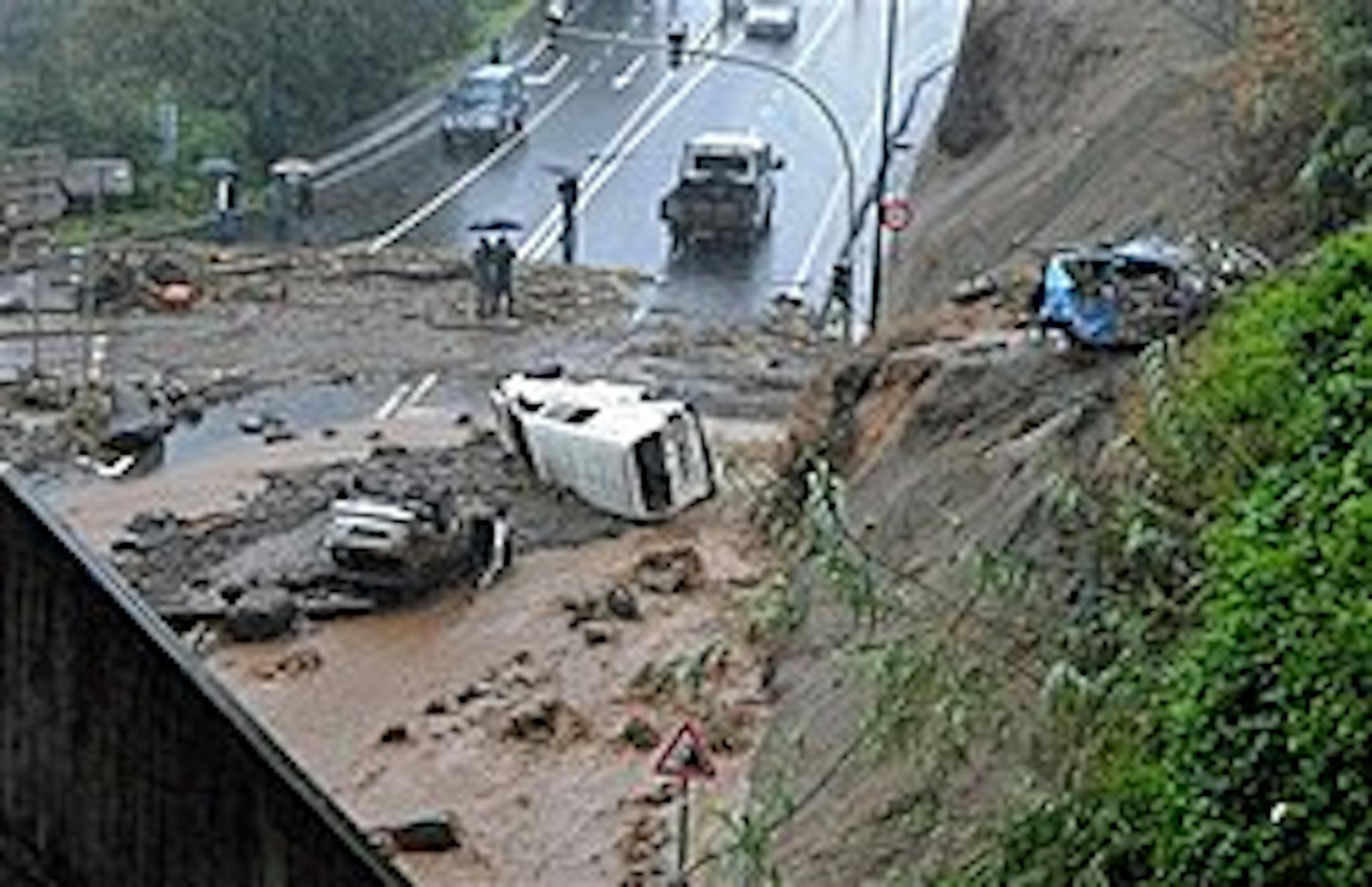 People look at cars carried down a hillside by floodwaters outside Funchal, the Madeira Island's capital, Saturday, Feb. 20 2010. Heavy rain caused flash floods all around the Portuguese island and the local government has confirmed 32 dead. (AP Photo/Octavio Passos)