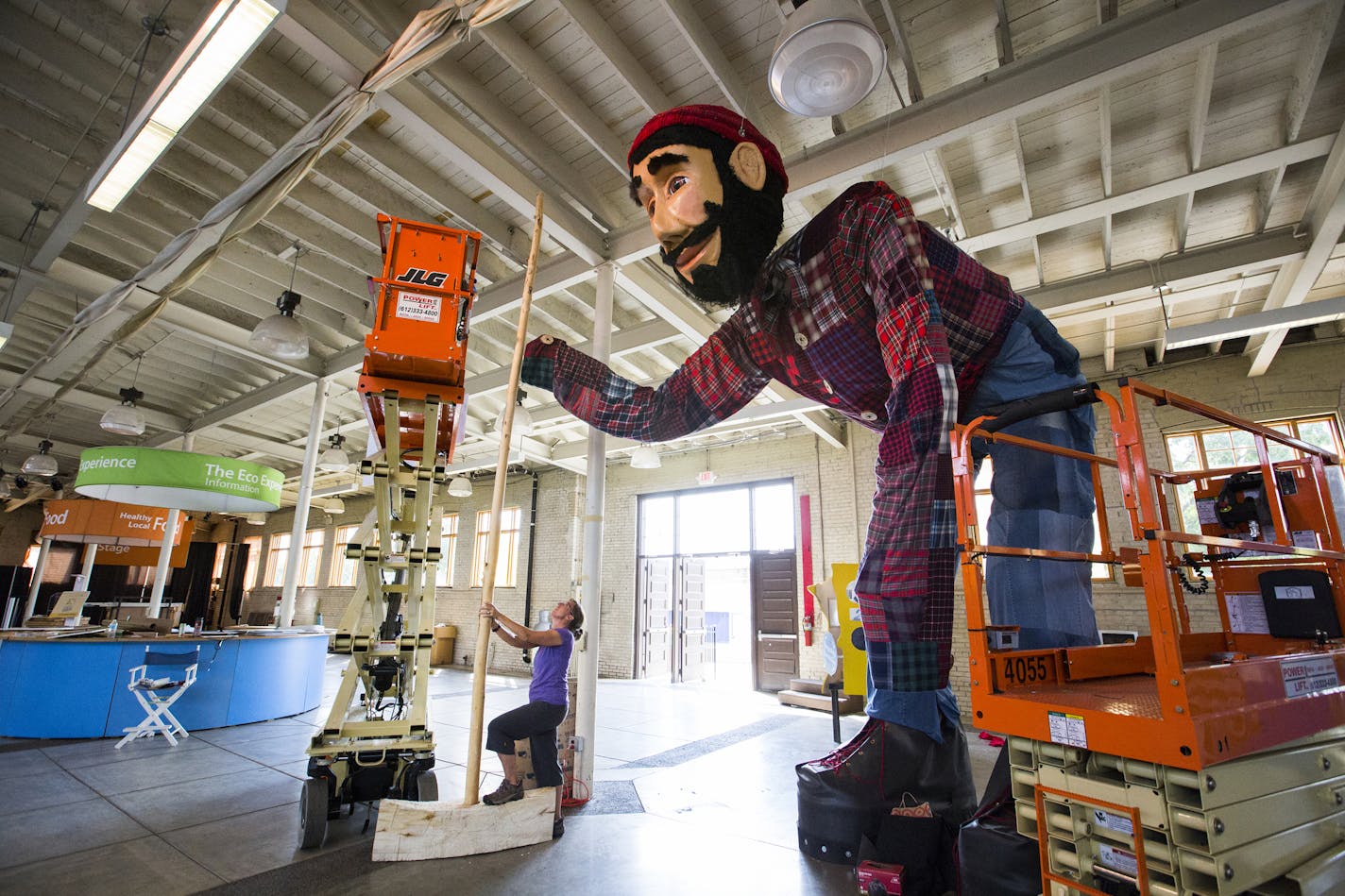 Jeanne Giernet of the Minnesota Pollution Control Agency sets up Paul Bunyan's ax, the handle of which is made from a small tree trunk and the blade carved with a chainsaw from a felled tree at the Eco Experience Building at the Stair Fairgrounds on Aug. 18.