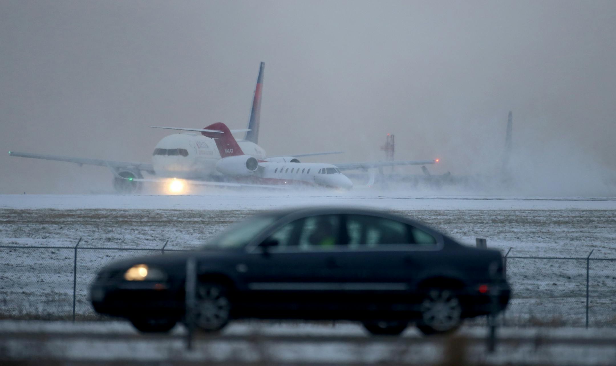 A vehicle navigates snow on Highway 77 as planes deal with blowing snow on a runway at MSP after an overnight snowfall Thursday, Nov. 29, 2018, in Richfield, MN.