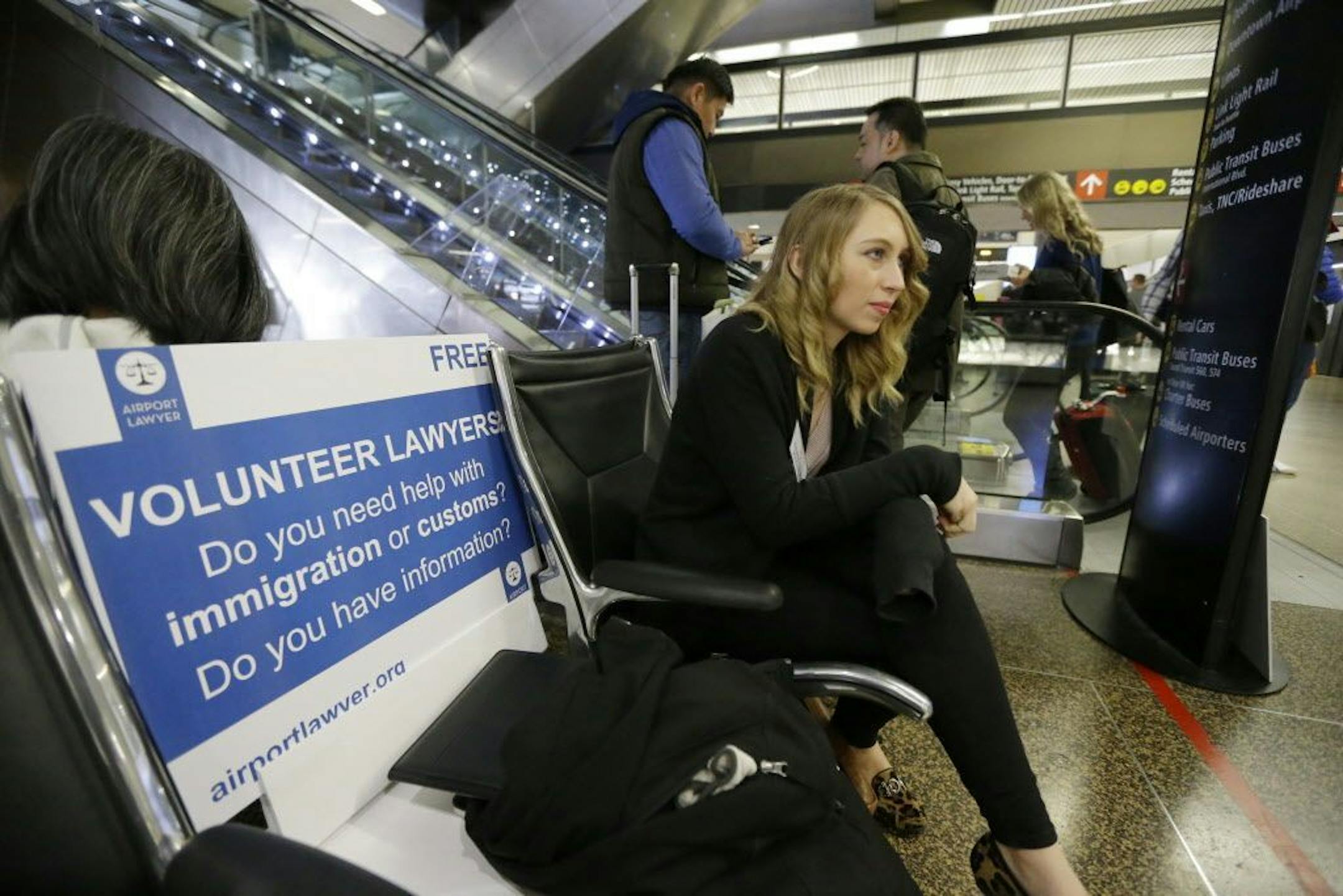 Asti Gallina, a volunteer law student from the University of Washington, sits at a station near where passengers arrive on international flights at Seattle-Tacoma International Airport, Tuesday, Feb. 28, 2017, in Seattle. Gallina was volunteering with the group Airport Lawyer, which also offers a secure website and mobile phone app that alerts volunteer lawyers to ensure travelers make it through customs without trouble. Airport officials and civil rights lawyers around the country are getting r