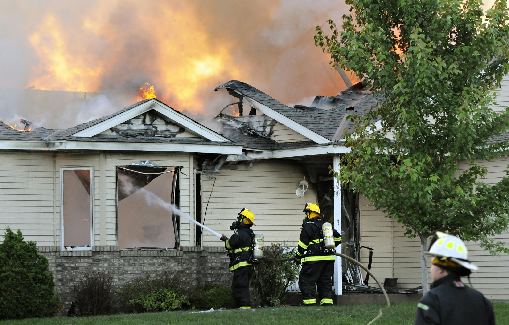 Firefighters from area departments battle the flames after a small plane crashed into a home at 731 Garden Place in Sauk Raids, Minn., Friday, June 20, 2014.