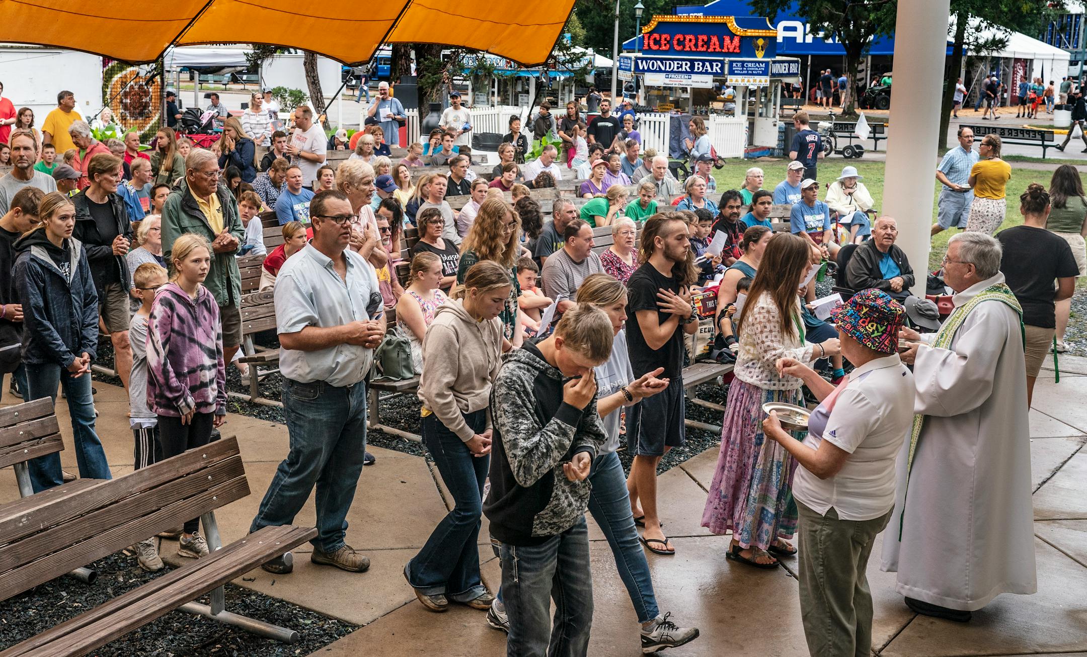 The Rev. Robert Fitzpatrick , right, and usher Teri Heyer distributed communion during a Mass celebrated at Baldwin Park on the Minnesota State Fairgrounds.