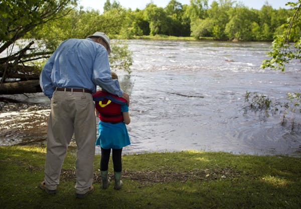 June 26, 2012: Len Anderson gave his granddaughter Logan, 7, some tips as she tried fishing on the flooded St. Louis River in Cloquet, Minn.