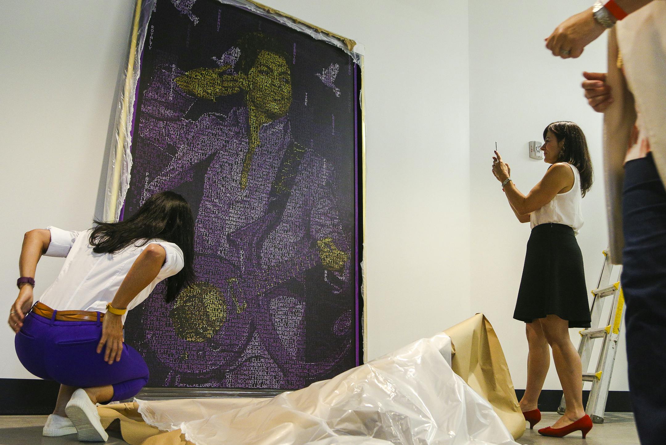 Members of the Minnesota Vikings staff take a closer look and photograph "Purple Reign" after its unveiling. ] Timothy Nwachukwu • timothy.nwachukwu@startribune.com "Purple Reign," a multidimensional acrylic paint on canvas portrait of Prince by artist Nicholas Schleif is hung inside the Pentair gate at U.S. Bank Stadium on Wednesday, July 20, 2016 in Minneapolis. The portrait is composed of Prince's lyrics to form elements including three doves, the Minneapolis skyline, a paisley pattern