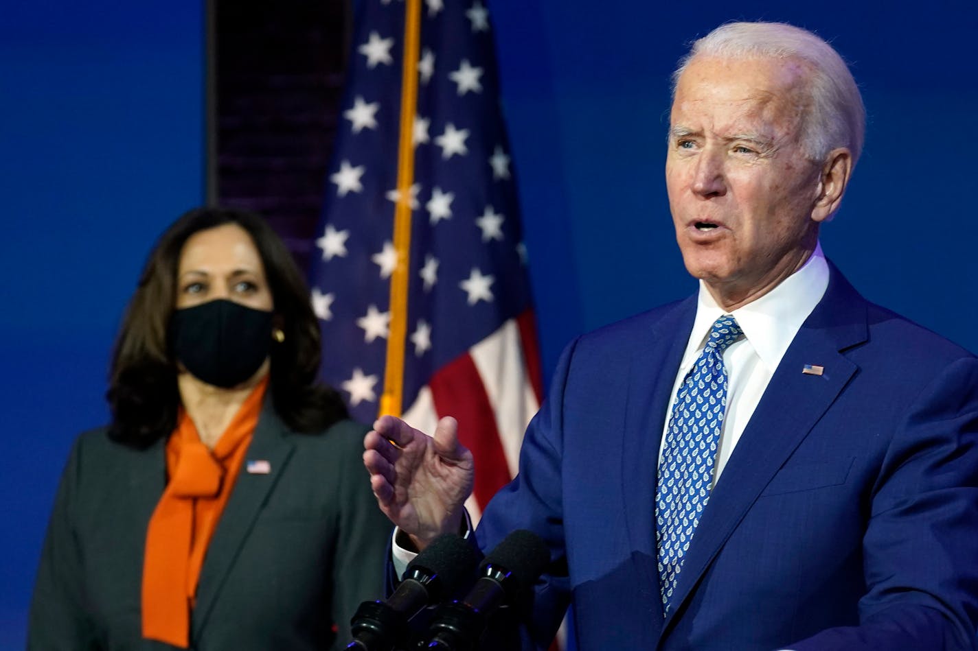 President-elect Joe Biden speaks Monday, Nov. 9, 2020, at The Queen theater in Wilmington, Del., as Vice President-elect Kamala Harris listens. (AP Photo/Carolyn Kaster)