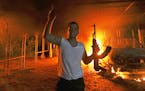 A protester reacts as the U.S. Consulate in Benghazi is seen in flames during a protest by an armed group.