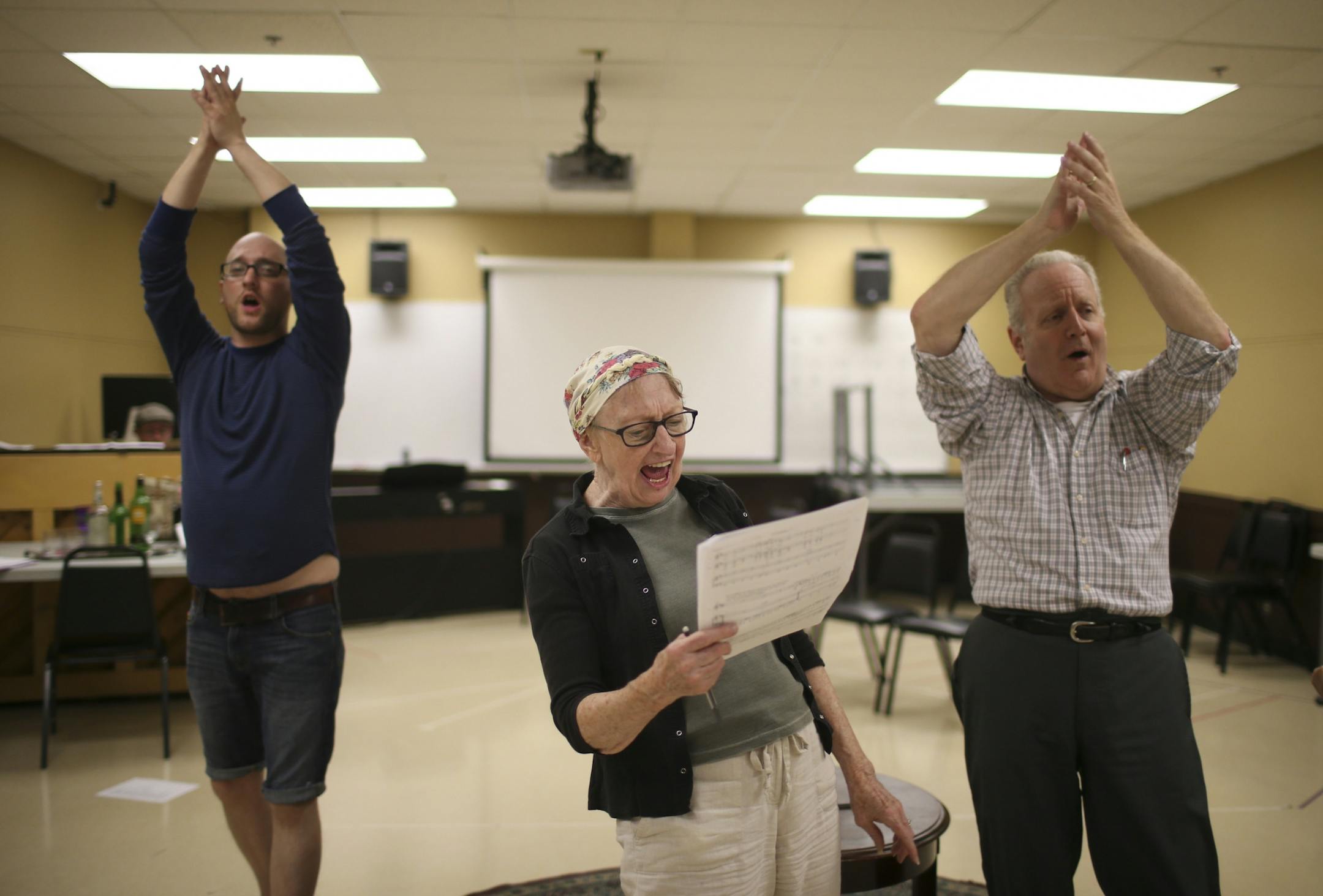 Adam Qualls, left, and Gary Briggle, danced while Wendy Lehr, playing a lawyer, sang, during rehearsal Wednesday night.