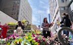 Maria Wait buys flowers from the Pflaum Farms stand on opening day of the Nicollet Mall farmers market in downtown Minneapolis.