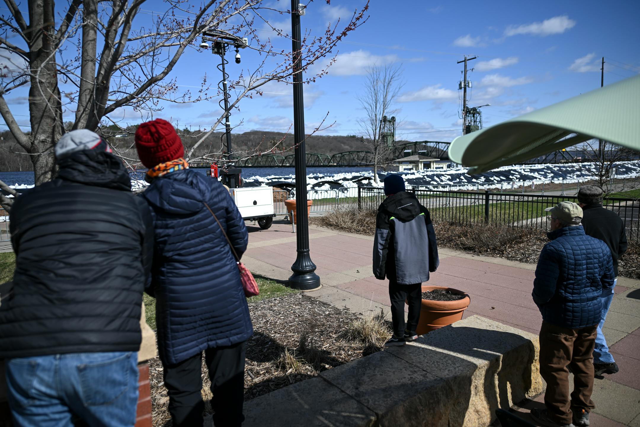 People gather to look at the rising waters of the St. Croix river beyond a dike Monday, April 17, 2023 in Stillwater, Minn.