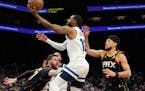 Minnesota Timberwolves guard Mike Conley, center, drives past Phoenix Suns guard Devin Booker, right, and Suns center Jusuf Nurkic, left, during the f