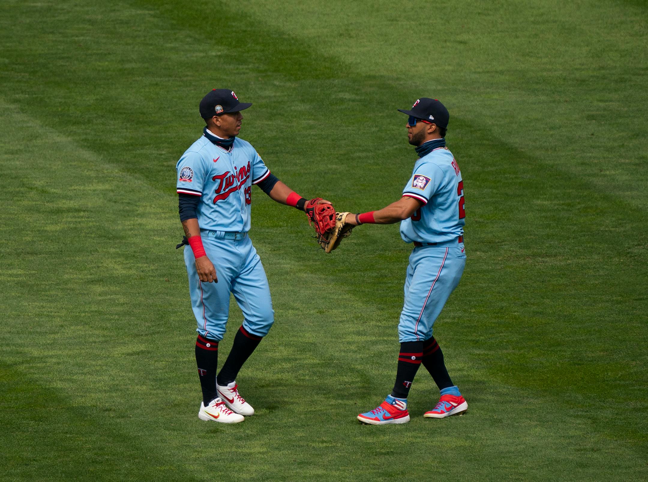 Minnesota Twins third baseman Ehire Adrianza (13) and left fielder Eddie Rosario (20) touched gloves after Adrianza caught a pop fly by Cleveland Indians third baseman Jose Ramirez in front of Rosario for the first out of the ninth inning.