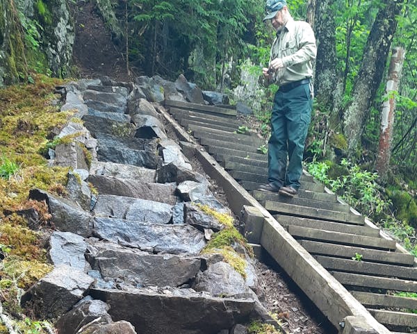 A Superior National Forest ranger stands on the old staircase, parallel to the new one.