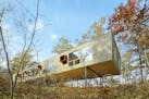 Architect Charlie Lazor's "Peek-a-Boo" cabin in New Auburn, Wisconsin (2007), elevated on metal legs, hides itself in the summery woods, only to reapp