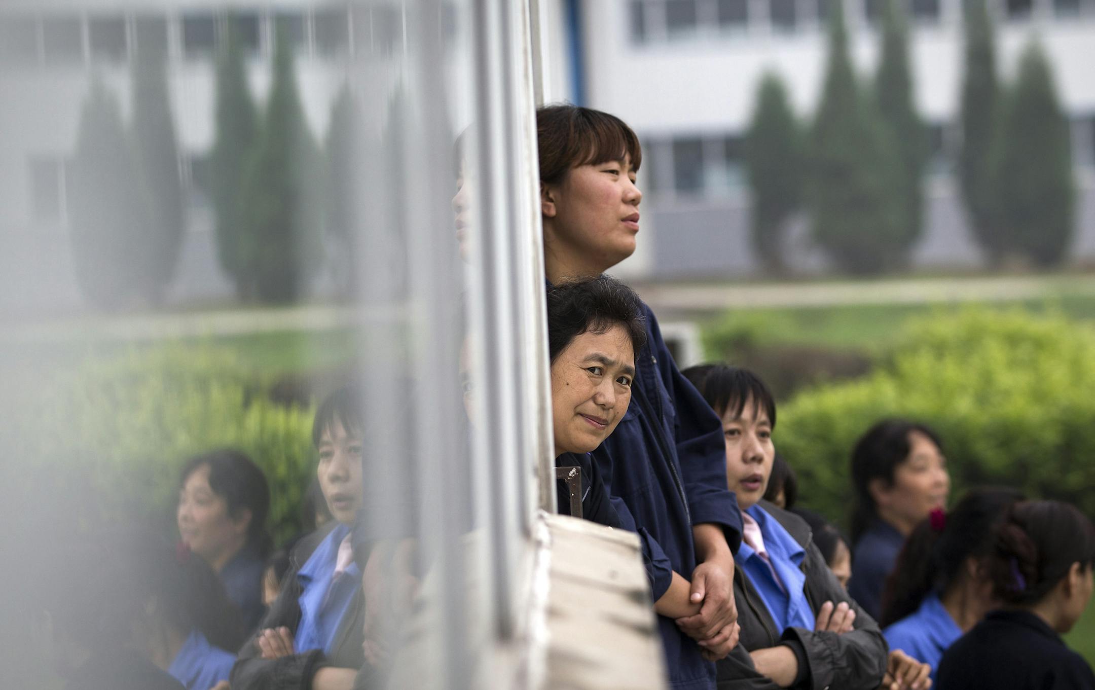 A worker looks out from a door with others at the Specialty Medical Supplies plant, where American Chip Starnes, a co-owner of Florida-based plant, is being held hostage at the Jinyurui Science and Technology Park in Qiao Zi township of Huairou District, on the outskirts of Beijing, China Tuesday, June 25, 2013. The American executive held in his Beijing medical supply plant by angry workers said Tuesday's he's waiting for his lawyers to arrive to resolve a compensation dispute that highlights t