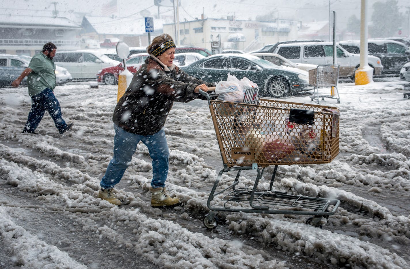 Brenda Nolting, of Rapid City, S.D., rolls her cart to her car after stocking up on necessities Friday, Oct. 4, 2013 at a local supermarket in Rapid City. An early snow storm has swept through Wyoming and western South Dakota, dropping more than a foot of snow in places. (AP Photo/Steve McEnroe)