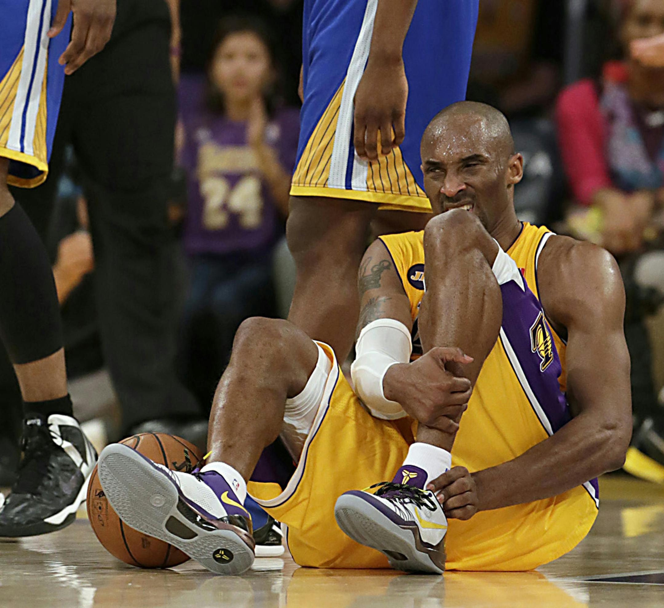 The Los Angeles Lakers' Kobe Bryant writhed in pain on the court late in the game against the Golden State Warriors at Staples Center in Los Angeles on April 12. Bryant now says, after Achilles surgery, that he might not be ready for the Lakers' season opener on Oct. 29.