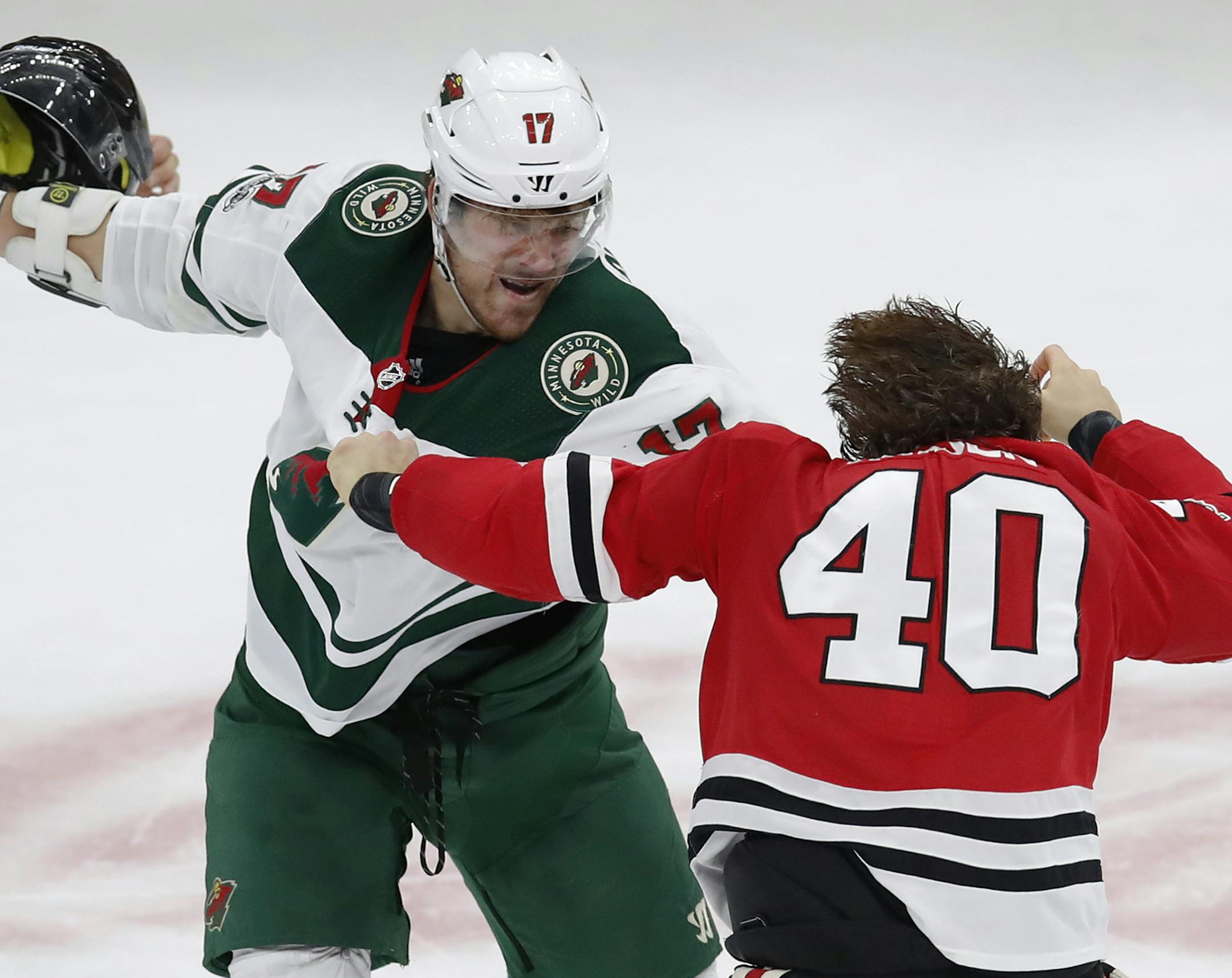 Minnesota Wild's Marcus Foligno, left, holds the helmet of Chicago Blackhawks' John Hayden during a fight in the second period of an NHL hockey game Thursday, Oct. 12, 2017, in Chicago. (AP Photo/Jim Young) ORG XMIT: MIN2017101221401072