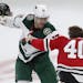 Minnesota Wild's Marcus Foligno, left, holds the helmet of Chicago Blackhawks' John Hayden during a fight in the second period of an NHL hockey game T