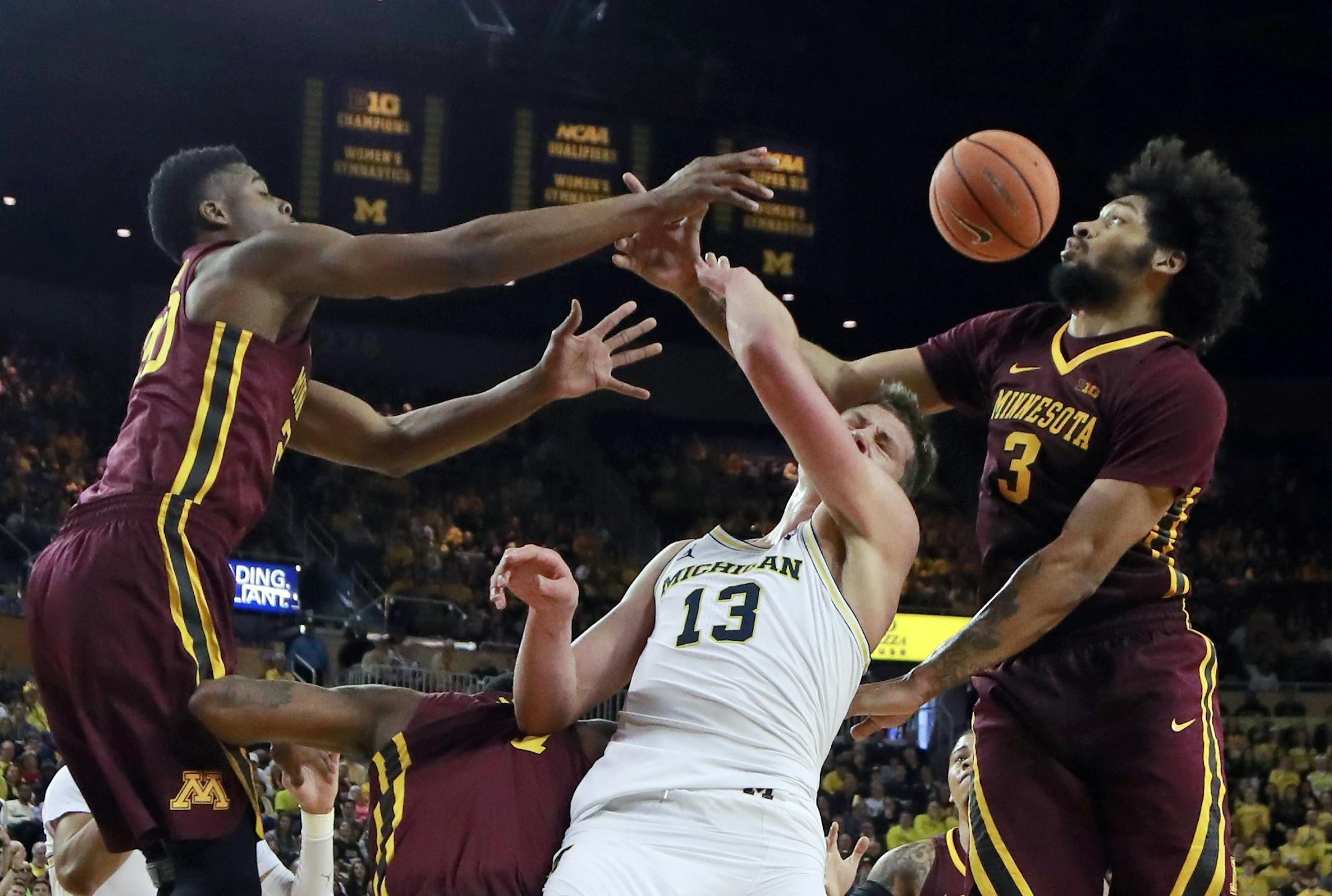 Minnesota forwards Davonte Fitzgerald, left, and Jordan Murphy, right, battle for a rebound with Michigan forward Moritz Wagner (13) during the second half of an NCAA college basketball game, Saturday, Feb. 3, 2018, in Ann Arbor, Mich. (AP Photo/Carlos Osorio)