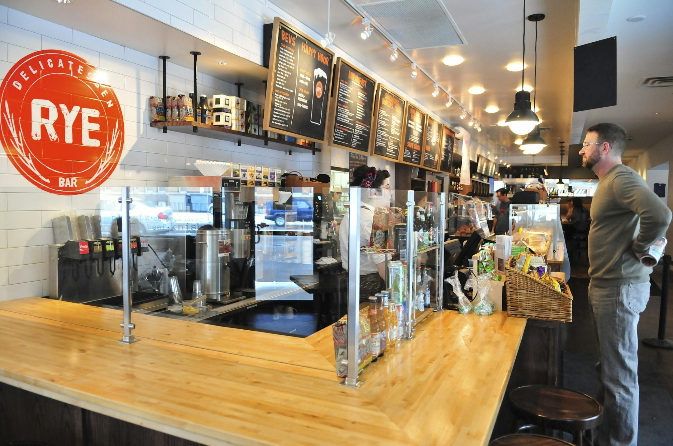 A customer orders lunch at the front counter at Rye, a deli in the Lowry Hill neighborhood.