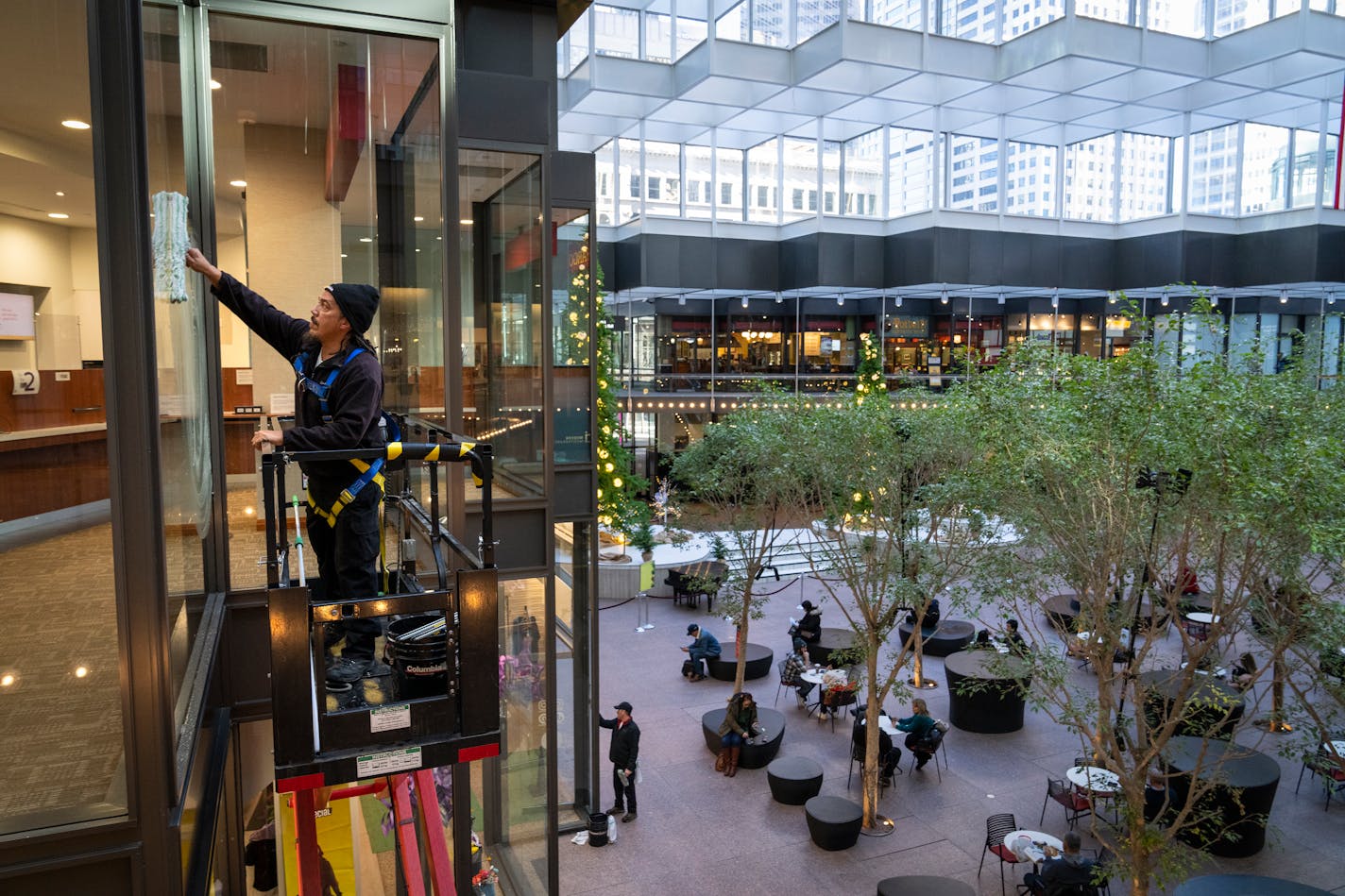 High-rise window cleaner Alex James from Columbia Building Services washes the interior windows of Crystal Court inside IDS Center in Minneapolis, Minn. Wednesday, Dec. 13, 2023. ] LEILA NAVIDI • leila.navidi@startribune.com