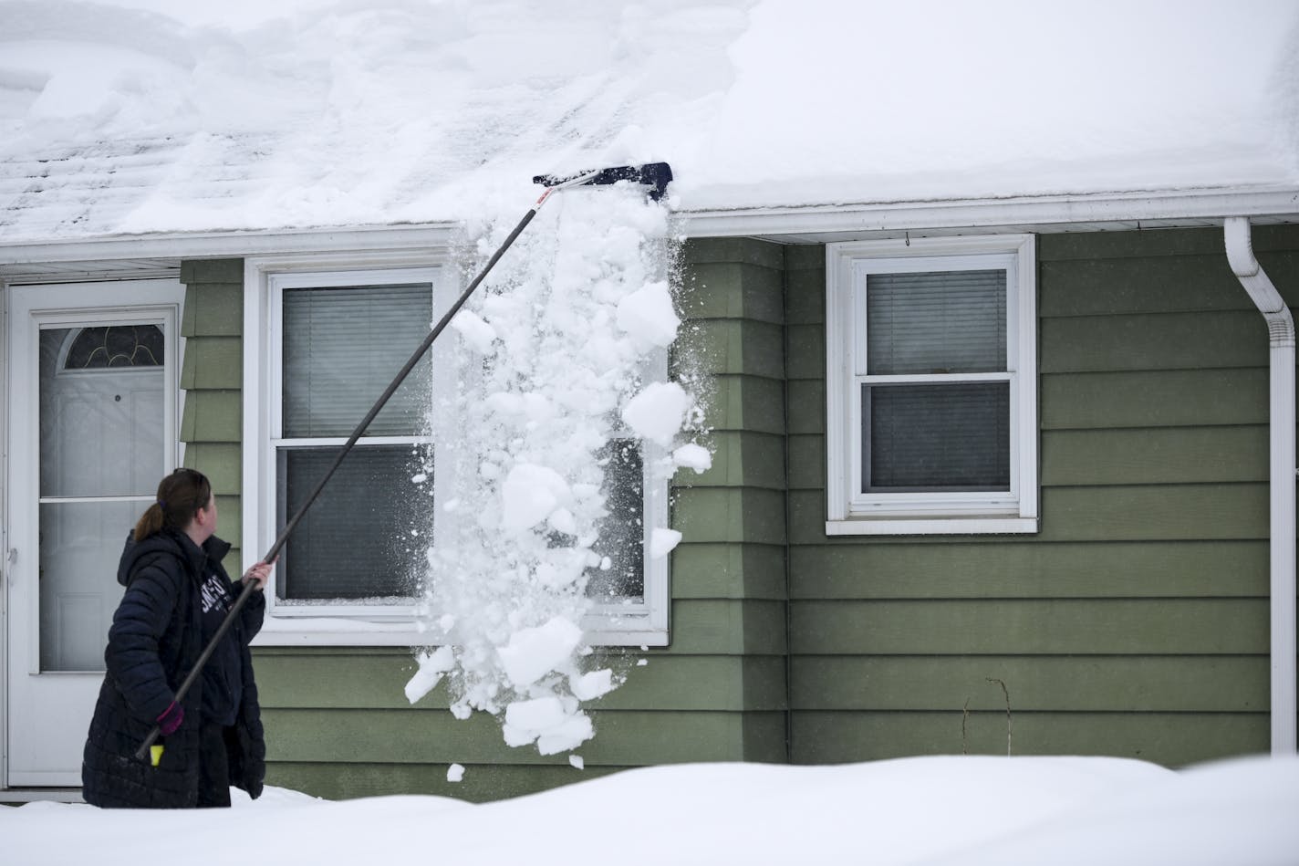 Angela Stanton of Robbinsdale removed snow from her roof to prevent ice dams from forming following the last snowstorm.