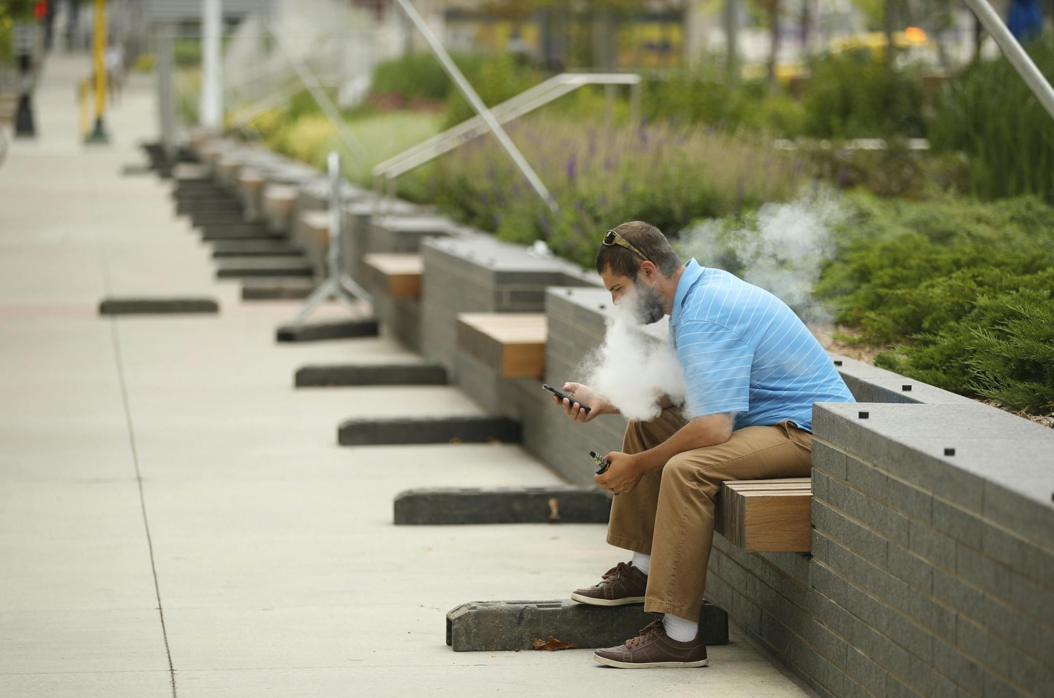A man sat along the wall bordering The Commons Park across from U.S. Bank Stadium.