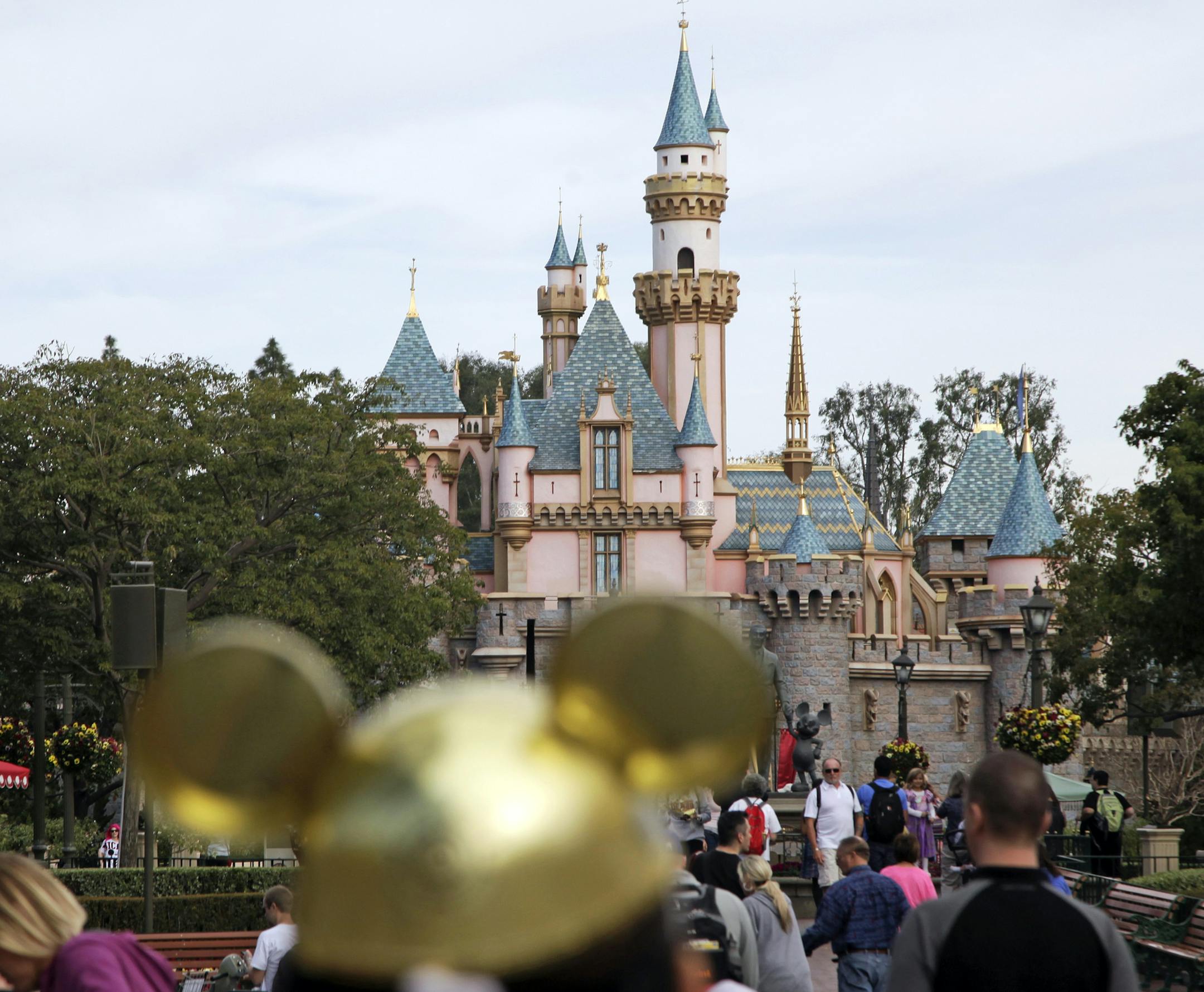 In this 2015 file photo, visitors walk toward the Sleeping Beauty's Castle in the background at Disneyland Resprt in Anaheim, Calif. Visiting Mickey and Minnie just got more expensive.