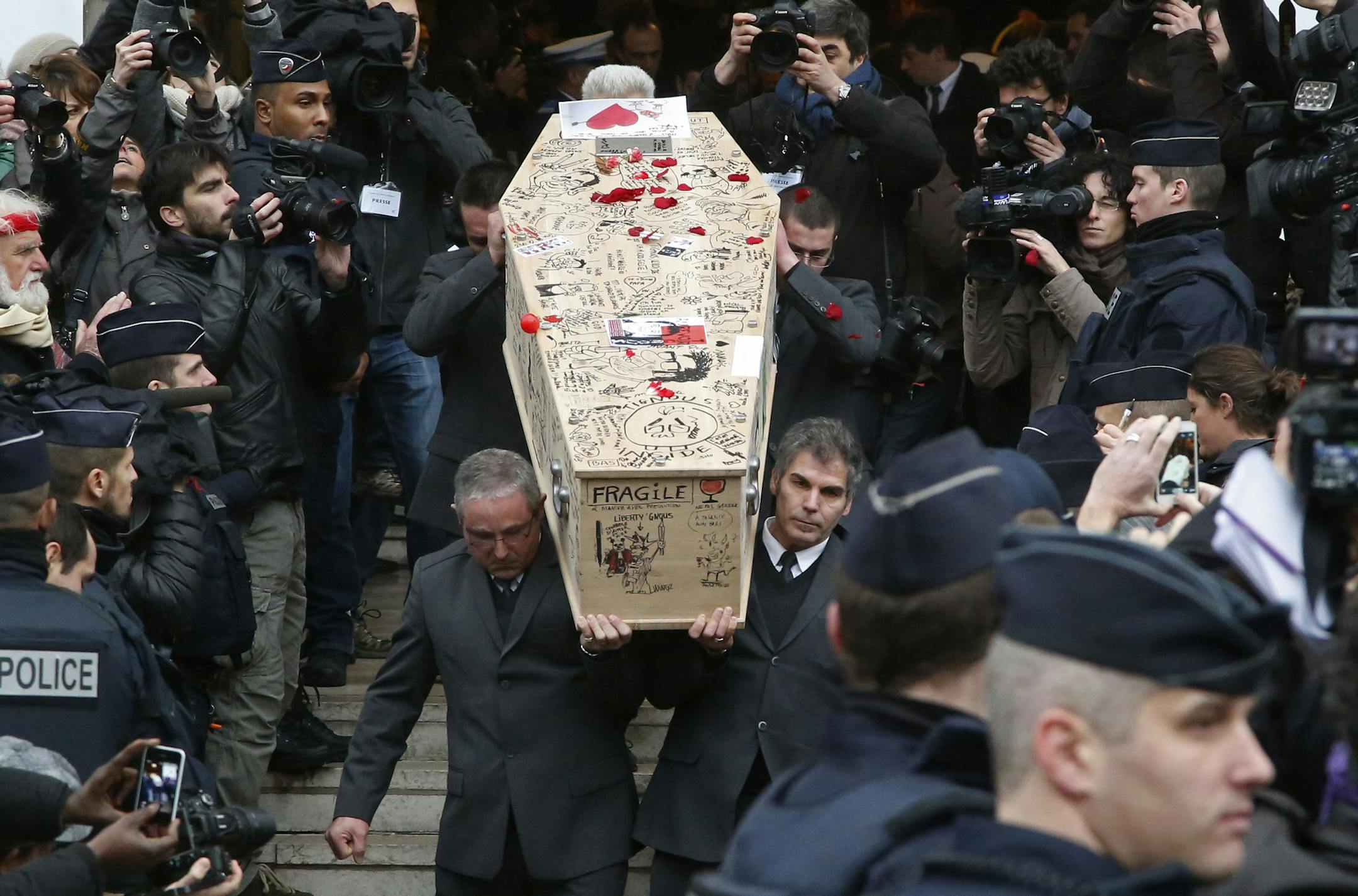 Pallbearers carry the casket of Charlie Hebdo cartoonist Bernard Verlhac, known as Tignous, decorated by friends and colleagues of the satirical newspaper Charlie Hebdo, at the city hall of Montreuil, outside east of Paris, Thursday, Jan. 15, 2015. Funerals are being held today for at least of the six staff members of the satirical newspaper Charlie Hebdo, who were killed last week in a terror attack on their offices in Paris. (AP Photo/Michel Euler)
