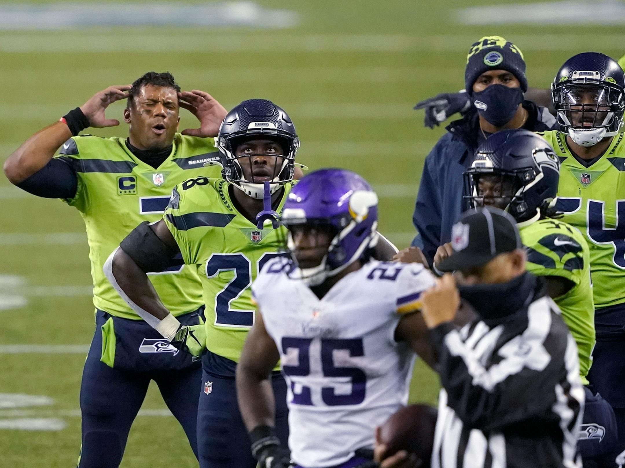 Seattle Seahawks quarterback Russell Wilson, left, and teammates wait with Minnesota Vikings players on the field for a final review of a play at the end of the second half of an NFL football game, Sunday, Oct. 11, 2020, in Seattle. The call went in the Seahawks' favor and they won 27-26. (AP Photo/Ted S. Warren)