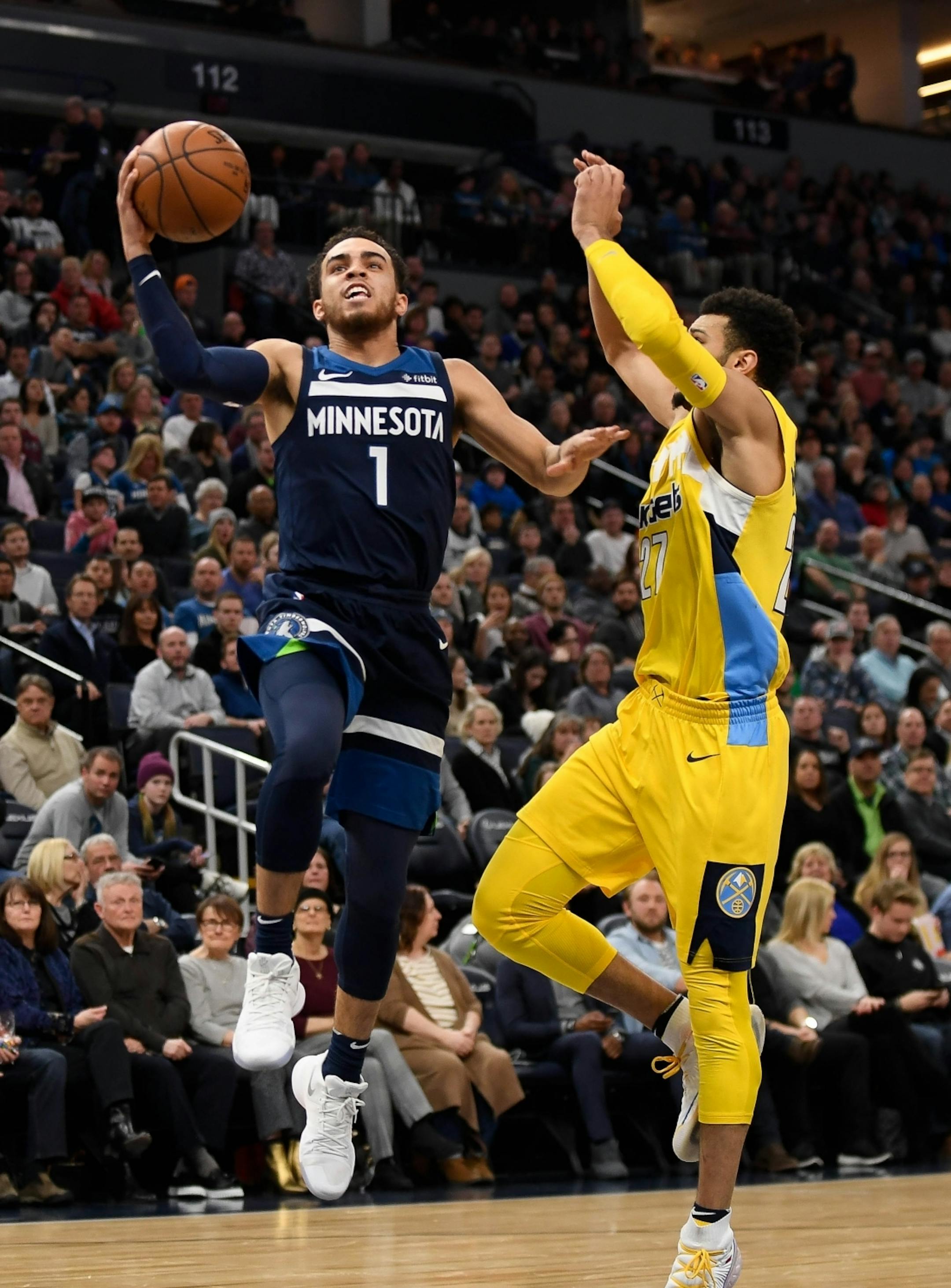 Minnesota Timberwolves guard Tyus Jones (1) scored a layup while being defended by Denver Nuggets guard Jamal Murray (27) in the second quarter.