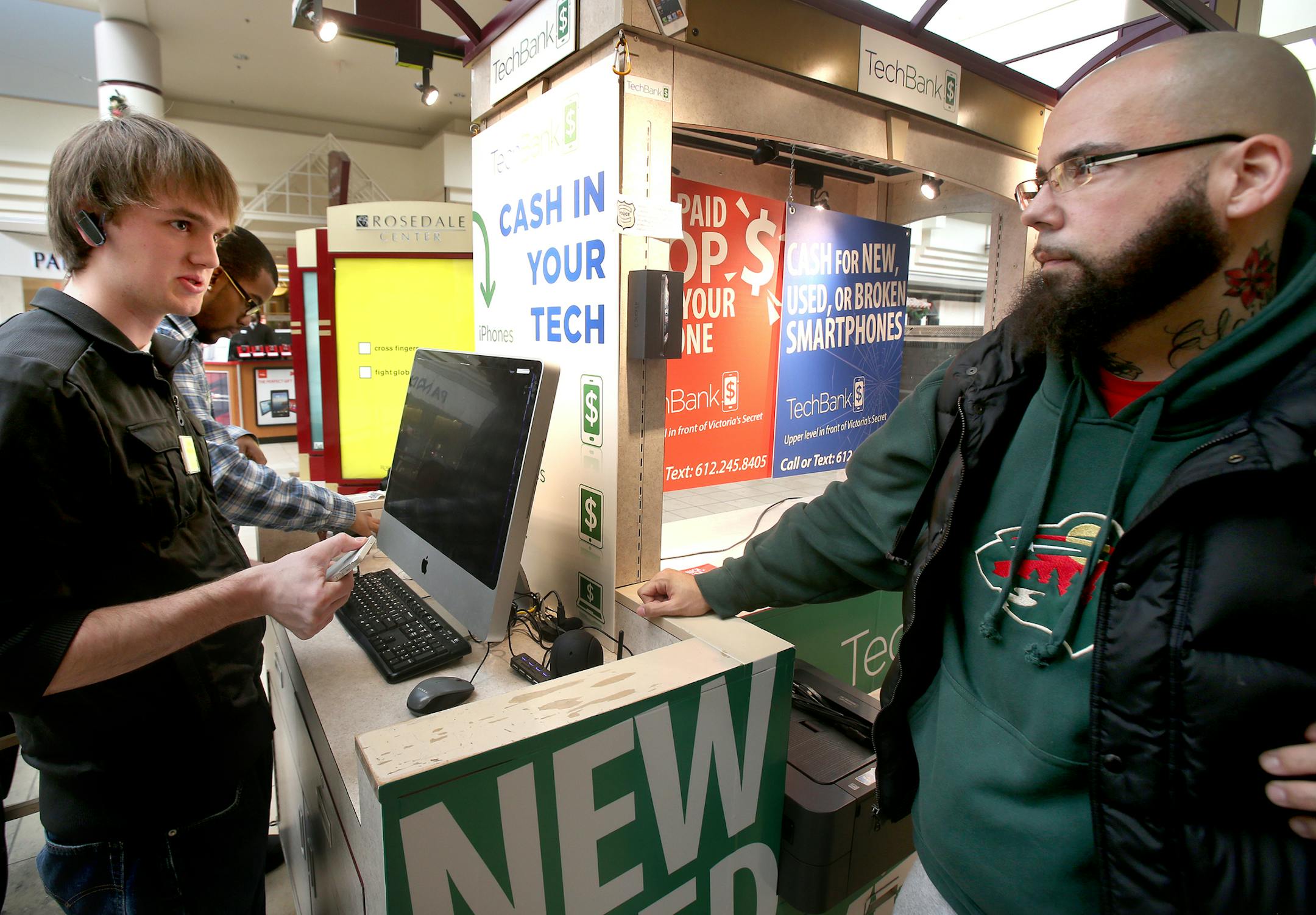 CJ Whidby of Woodbury (right), "I checked all over the internet and found that TechBank gave me the best deal for my phones." CJ Whidby (right) of Woodbury and owner of Push Muzic brought in seven phones from his business after his company changed phone service. CJ worked with Co-owner Austin White-Pentony, (left, at computer) and Sales Associate James Morris (middle) of TechBank in Rosedale Center. Roseville, MN on December 9, 2013. ] JOELKOYAMA‚Ä¢jkoyama@startribune