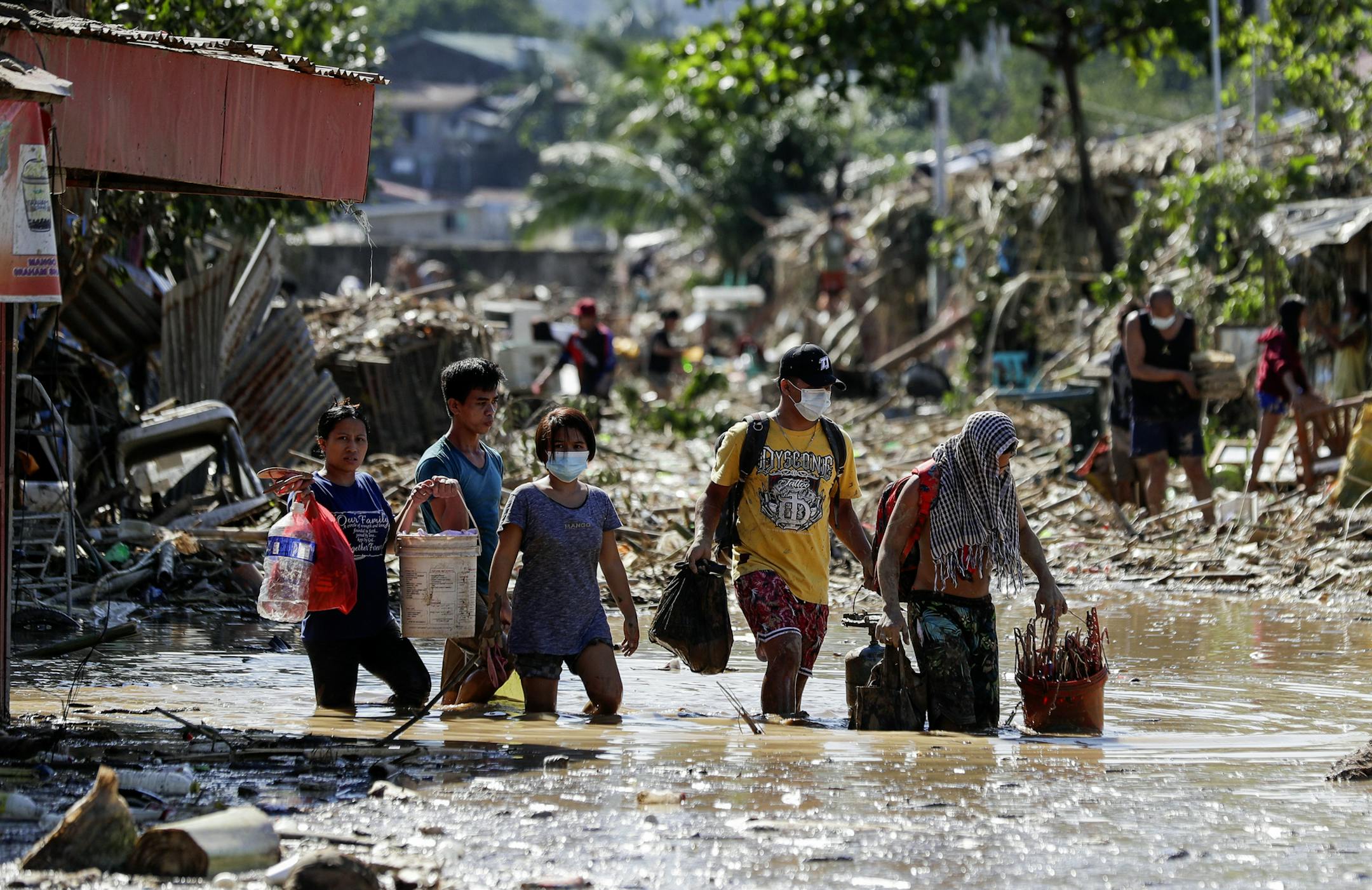 Residents walk on mud and debris as they retrieve belongings from their homes at the typhoon-damaged Kasiglahan village in Rodriguez, Rizal province, Philippines on Friday, Nov. 13, 2020. Thick mud and debris coated many villages around the Philippine capital Friday after Typhoon Vamco caused extensive flooding that sent residents fleeing to their roofs and killing dozens of people.