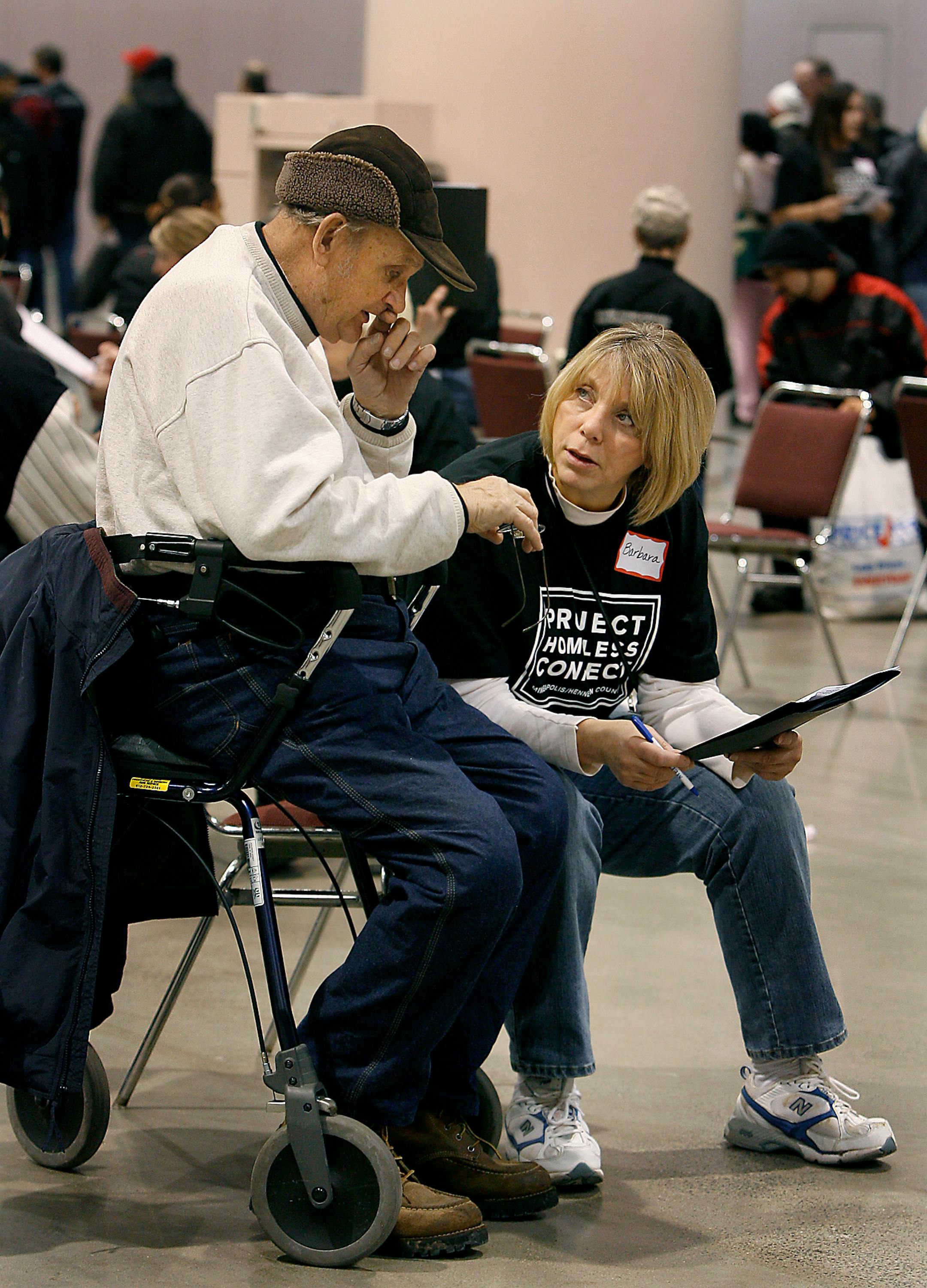 Volunteer Barbara Deese went over services available at Project Homeless Connect with Henry Werner at the Minneapolis event on Monday.