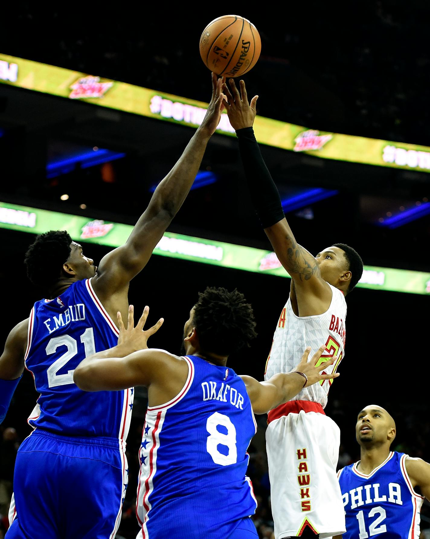 Atlanta Hawks' Kent Bazemore (24) takes a shot over Philadelphia 76ers' Joel Embiid (21) and Jahlil Okafor (8) during the first half of an NBA basketball game, Saturday, Oct. 29, 2016, in Philadelphia. (AP Photo/Michael Perez)