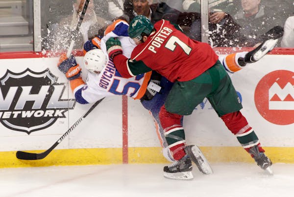 New York Islanders defenseman Johnny Boychuk (55) is checked into the boards by Minnesota Wild left wing Chris Porter (7) during the first period of a