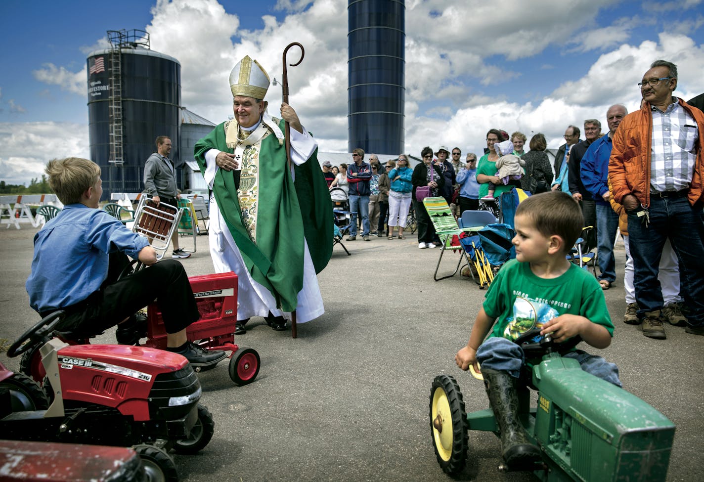 Archbishop Bernard Hebda is known for being an accessible bishop. Here, he chats with Simon Strand, 11, after the Rural Life Mass at the Dahlheimer farm in Center City, Minn. Gabe Pratt, 3, is at right.