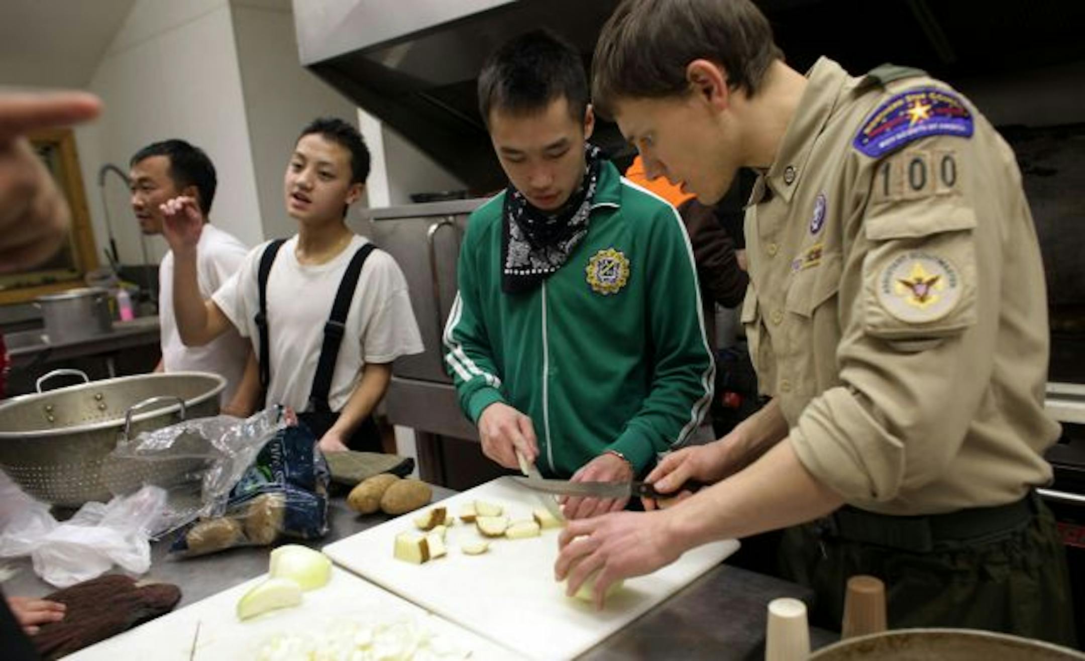 Head scout Xao Thao received cooking instructions from assistant scout master Thomas Evans as they prepared lunch for troop leaders at Camp Ajawah.
