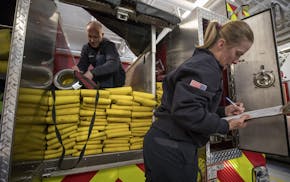 Debralyn Bryant, a volunteer firefighter, took notes as engineer Brian Costello packed up hoses in Inver Grove Heights. Many departments are strugglin